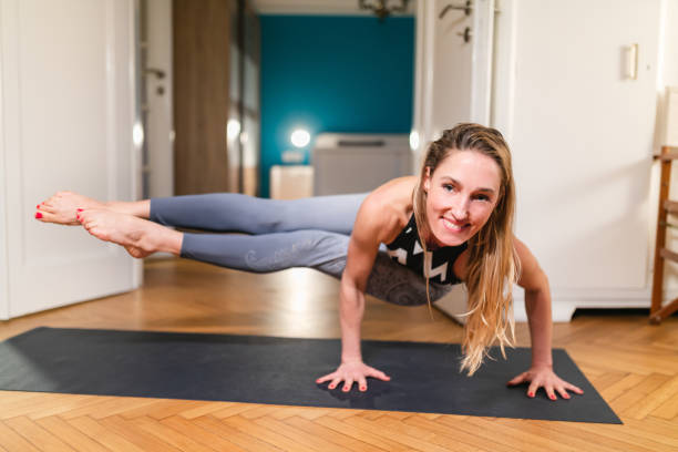 istock Smiling woman doing yoga at home in eight angle pose 1299949867