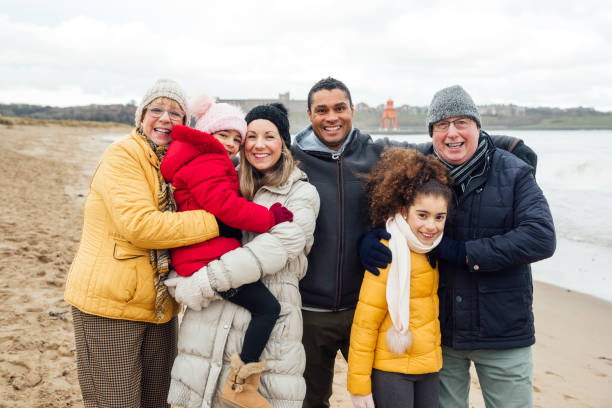 Happy Three Gen Family Three gen family portrait. They are standing together embracing while on a winter walk at the beach in the North East of England. northeastern england photos stock pictures, royalty-free photos & images