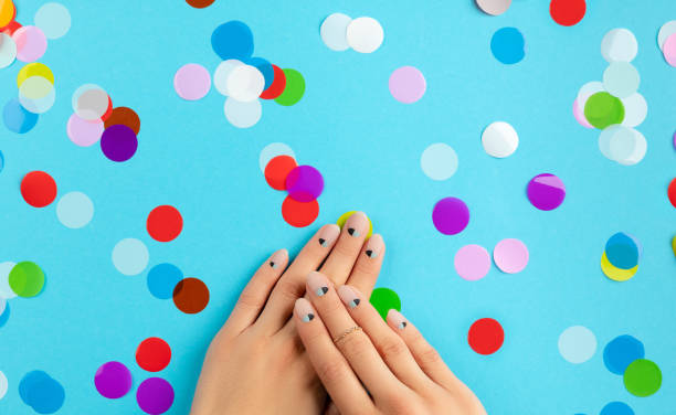 istock Womans hands with colorful confetti over blue background. 1299955240