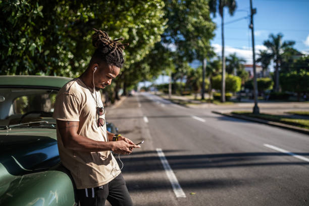 istock Young man using smartphone on the street next to retro car 1299957338
