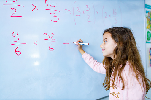 Child writing mathematics on whiteboard in the classroom