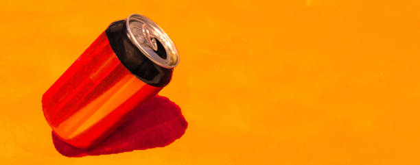 istock a red and black soda can tilted with orange background 1299958490