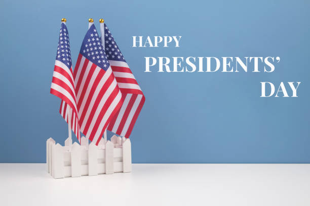 istock Creative composition with USA flags on white table with blue wall background - Presidents' Day 2021 concept 1299959300