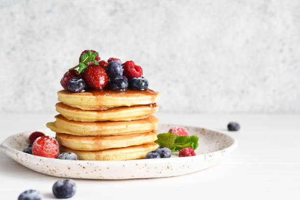 istock Pancakes with berries and maple syrup for breakfast on a light background. 1299960145