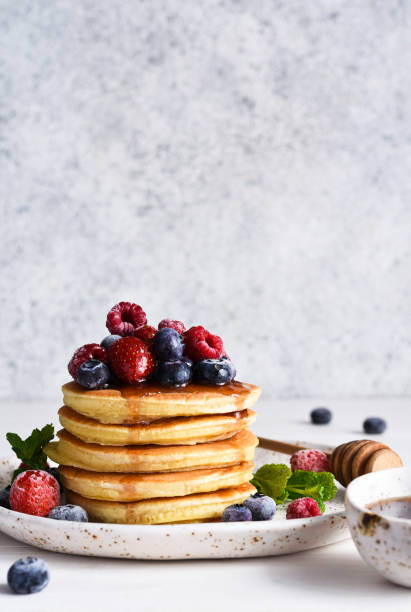istock Pancakes with berries and maple syrup for breakfast on a light background. 1299960153