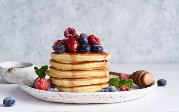 istock Pancakes with berries and maple syrup for breakfast on a light background. 1299960165