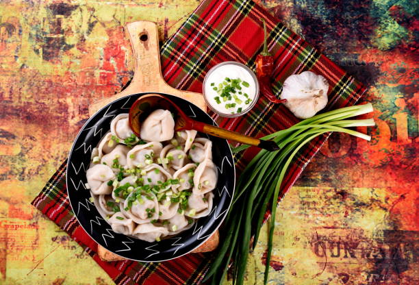 Cooked Meat dumplings - russian pelmeni Cooked Meat dumplings (russian pelmeni) with green onion and sour cream on a plate, vintage background russian pelmeni stock pictures, royalty-free photos & images