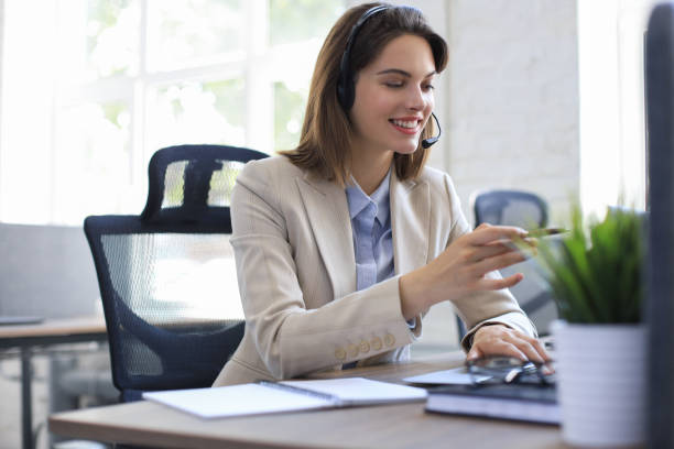 istock Beautiful smiling call center worker in headphones is working at modern office 1299961918