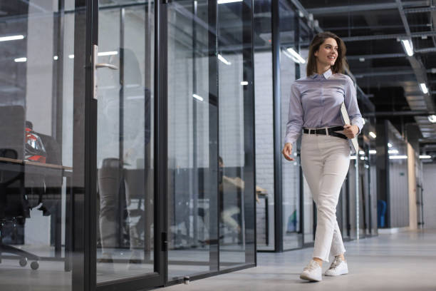 istock Businesswoman walking along the office corridor with documents. 1299962148