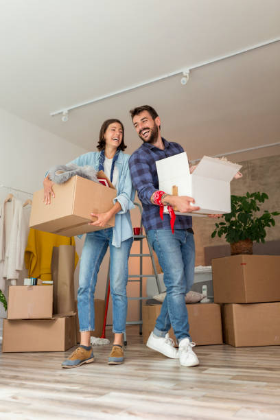 istock Couple carrying boxes while moving in together 1299964380