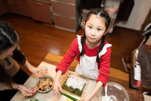 istock Mother and daughter making sushi rolls 1299964483