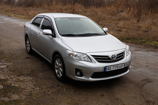 Dnipro, Ukraine - January 25, 2021: Toyota Corolla 2011, bright grey color, car in the rain