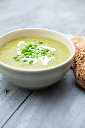 Healthy lunchtime meal of pea and ham soup, with cream and seeded kaiser rolls