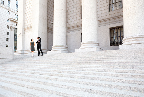 Two women in discussion on the exterior steps of a courthouse. Could be lawyers, business people etc.