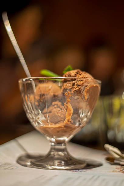 istock chocolate ice cream with kerob in glass bowl on blurred background, vertical 1299967124