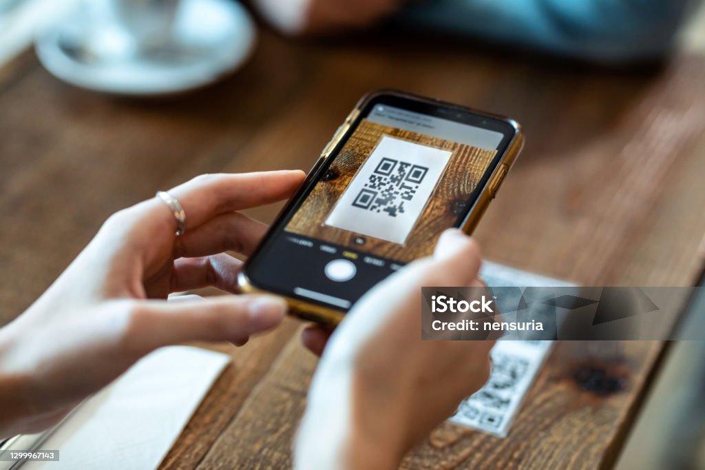 Young woman hands using the smart phone to scan the qr code to select food menu in the restaurant. Close up of young woman hands using the smart phone to scan the qr code to select food menu in the restaurant. QR Code Stock Photo
