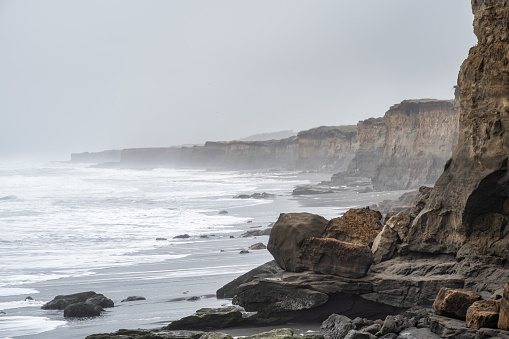 Cliffs on the coastline of Porma beach on a foggy day in La Araucania region, southern Chile