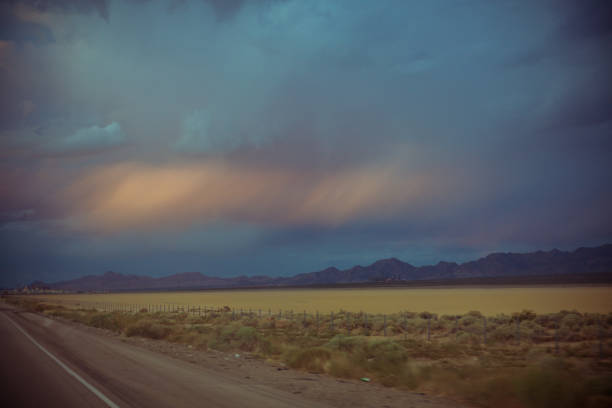 una lunga strada dritta in nevada - arid climate asphalt barren blue foto e immagini stock