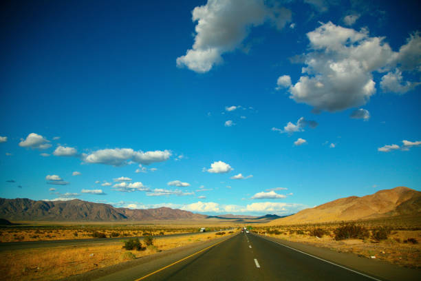 una lunga strada dritta in nevada - arid climate asphalt barren blue foto e immagini stock