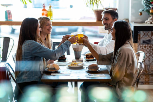 Happy young friends group toasting with beer to celebrating good news while having fun in a restaurant. Shot of happy young friends group toasting with beer to celebrating good news while having fun in a restaurant. spanish hamburger stock pictures, royalty-free photos & images