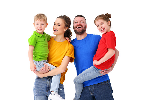 Smiling parents and kids wearing t shirts of different colors standing on white background in studio and looking at camera