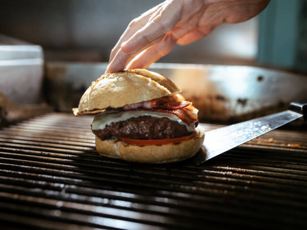 istock Hand's chef preparing delicious burger on grilled in the restaurant kitchen. 1299968909
