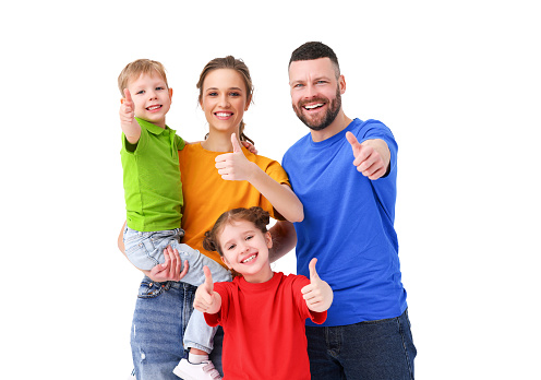 United happy parents and adorable kids showing thumb up gesture while standing on white background in studio and looking at camera