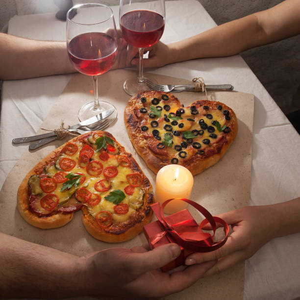 Romantic love heart shaped pizza dinner and giving gifts stock photo
