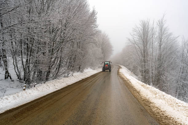 istock Tractor on the road at forest in winter 1299970313