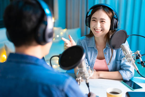 people make podcast in studio asian woman and man with microphone are recording podcast at studio in the evening radio dj stock pictures, royalty-free photos & images