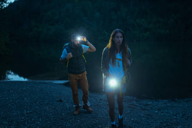 istock Two hikers holding flashlights standing by the lake 1299971555