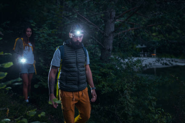 istock Couple walking through the woods with flashlights and backpacks 1299971613
