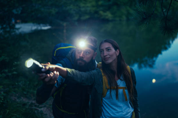 istock Couple holding together a flashlight outdoors in the nature 1299971662