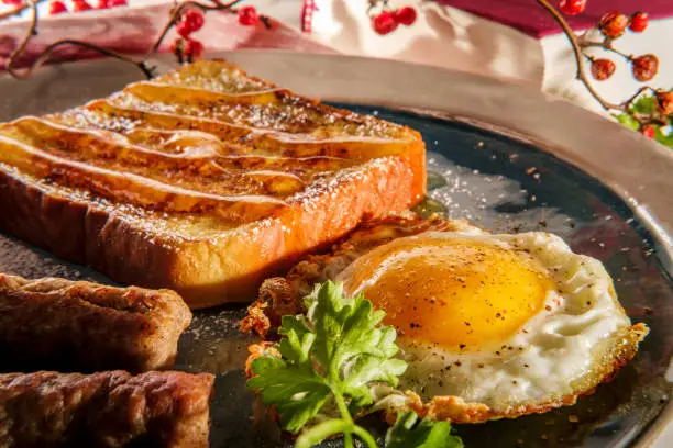 Classic American breakfast French toast with maple syrup served with side of sausage links and fried egg sunny side up