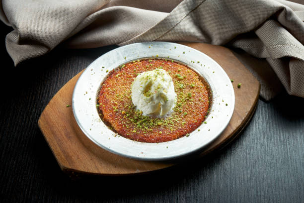 Appetizing Turkish sweetness Kanafeh made with shredded filo pastry with honey, pistachios and white ice cream stock photo
