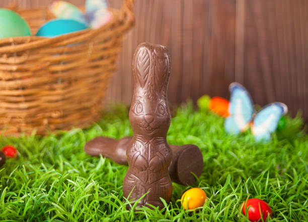 istock Easter chocolate bunny, carrots candy in the grass on the wooden background 1299973370