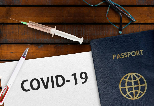 istock Paper width word covid-19, passport and vaccine on table. 1299974103