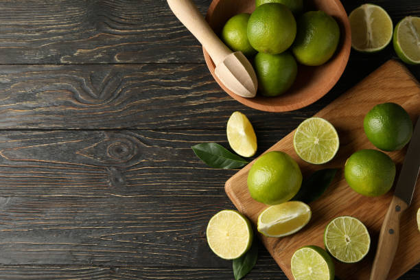 istock Bowl and board with lime on wooden background, space for text 1299974284