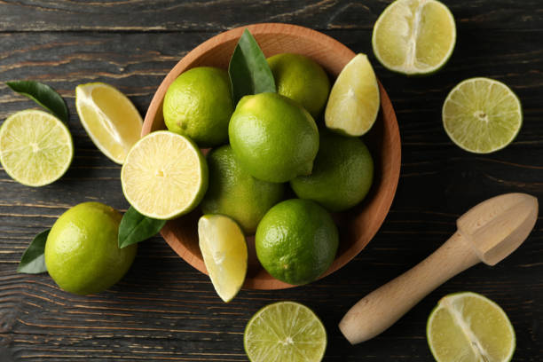 istock Bowl with ripe lime on wooden background, top view 1299974311