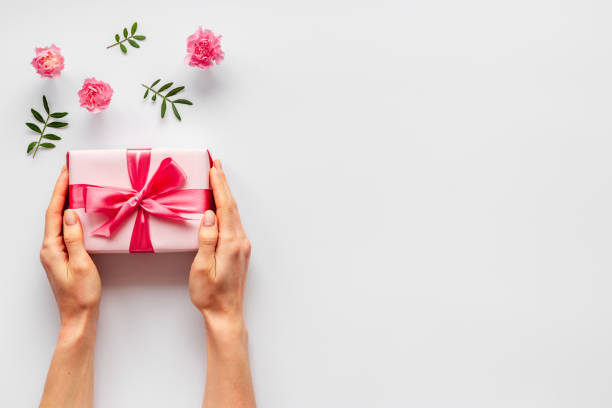 istock Valentines Day gift box in hands with flowers, top view 1299974674
