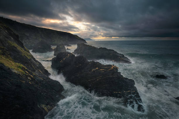 Stormy seascape sunset scene with black rocks stock photo
