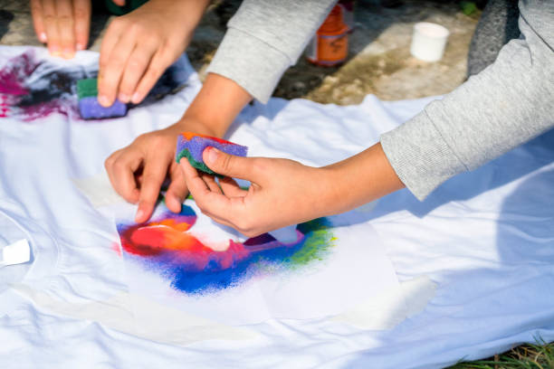 istock Creating your own t-shirt workshop outside. Hand applying paint on shirt 1299974843