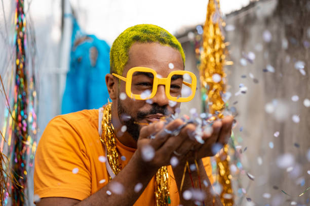 istock Man blowing out confetti at carnival at home 1299976163
