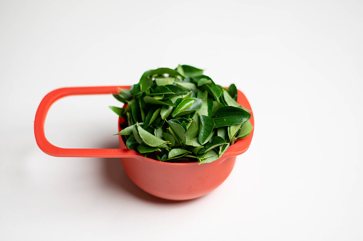 fresh curry leaves in a red colour cup