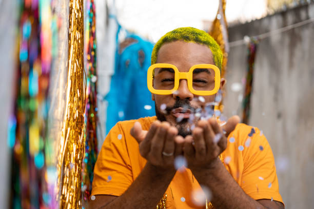 istock Man blowing out confetti at carnival at home 1299976196