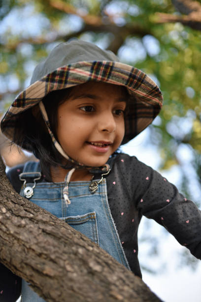 istock Low angle view of a cute girl climbing on a tree 1299978538