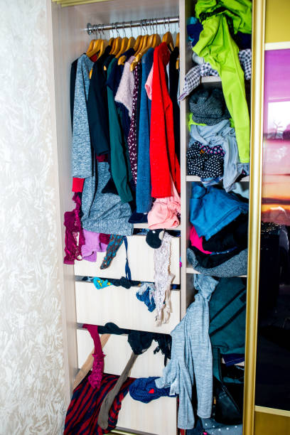 istock Mess in the wardrobe. Decluttering wardrobe. Sorting second-hand clothes for recycling. 1299979447