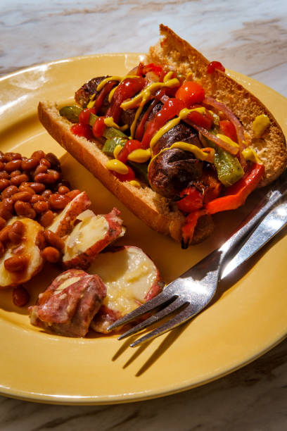Sausage Onions Peppers Hoagie Sausage onions and peppers hoagie sandwich with side of baked beans and German potato salad torpedo sandwich stock pictures, royalty-free photos & images