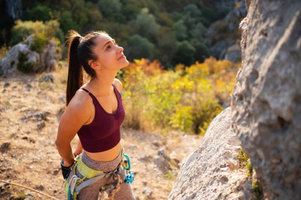 Sporty girl with special equipment climbs up on the rock wall