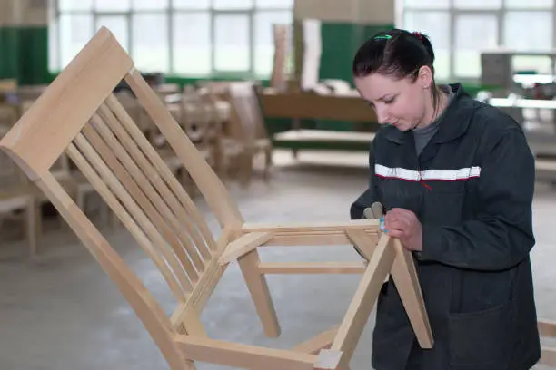 Photo of The employee of the furniture department polishes the chair with a nazhdachka. Furniture manufacture